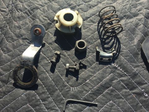 1978 Ford Bronco - Various vehicle parts are displayed on a quilted mat, including a spring, bracket, and hardware.