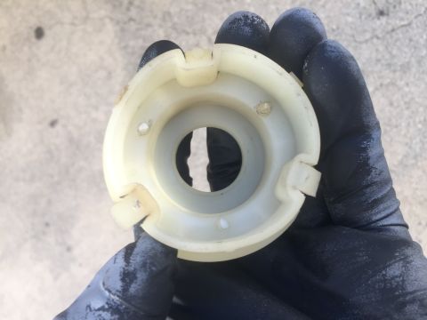 1978 Ford Bronco - A gloved hand holds a white plastic component, possibly from a vehicle's engine bay.