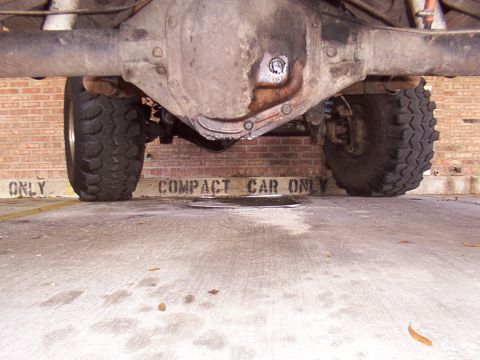 1991 Ford Bronco - The underside of a truck, showing its rear axle and tires, with a sign indicating it is not a compact car.