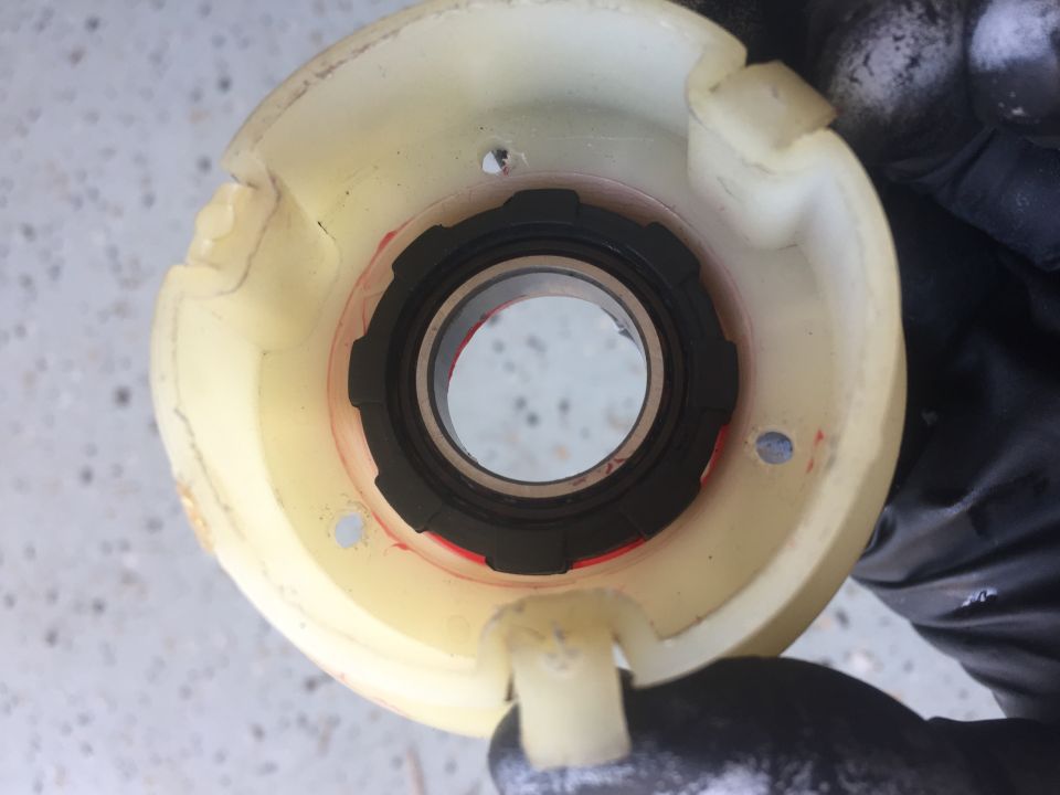 Bearing housing with black seal and red markings, held by gloved hand