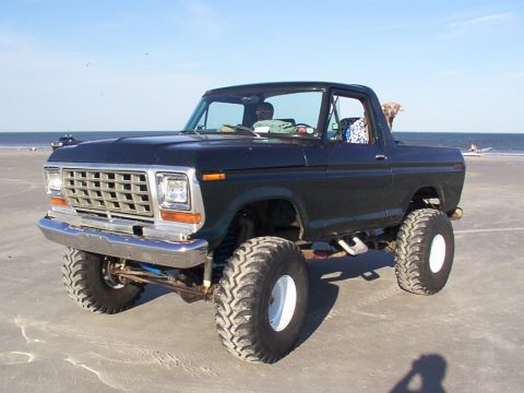 1991 Ford Bronco - This lifted Bronco, likely from the late 1970s, enjoys a day at the beach with a dog in the passenger seat.