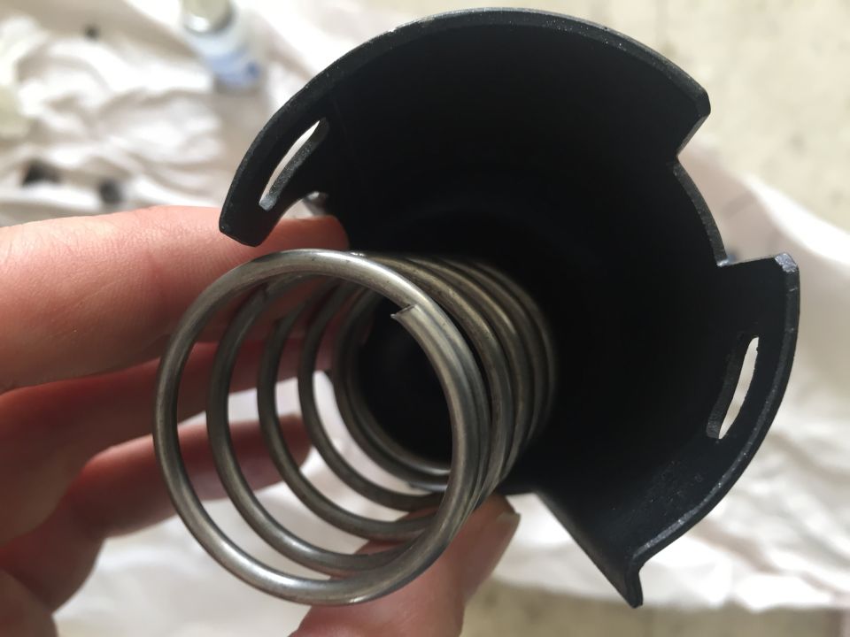 Close-up of a spring inside a black housing, held by a hand