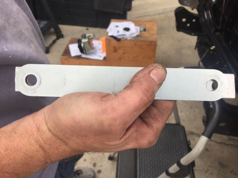 1978 Ford Bronco - A metal bracket is held in a hand, with a wooden box and papers visible in the background.
