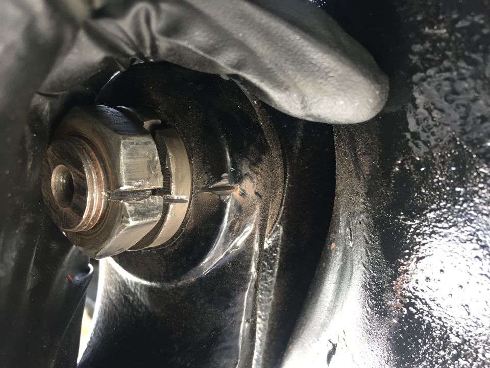 Close-up of a splined nut on a wheel hub assembly, with a gloved hand visible