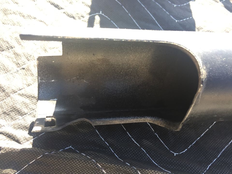 Close-up of a dark, hollow metal pipe section with a cut opening