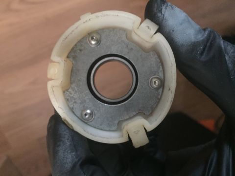 1978 Ford Bronco - A white plastic steering column component with a metal plate is held by a gloved hand.