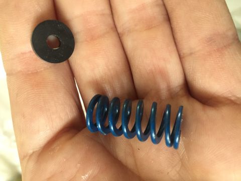 1978 Ford Bronco - A blue coil spring and a black washer are shown in a person's hand.