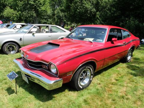 1971 Ford Ranchero - A red coupe with a prominent hood scoop and side stripes is displayed at an outdoor event.