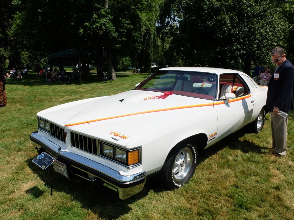 White 1976 Pontiac Grand Am with orange and red pinstriping, hood scoop, and red interior