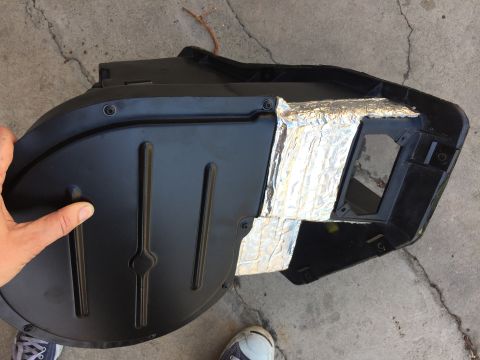 1978 Ford Bronco - A person holds a black plastic automotive HVAC duct that has been covered with silver insulation tape.