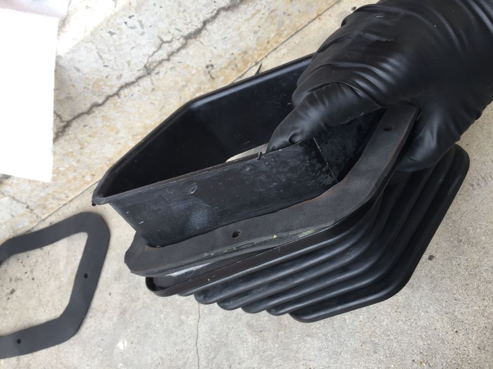 Gloved hand holding a black rubber seal and a black plastic housing with ribbed bellows
