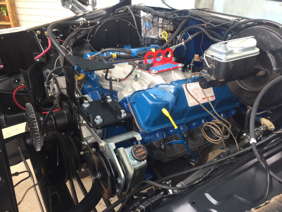 Engine bay with blue painted engine components, power steering reservoir, and belts