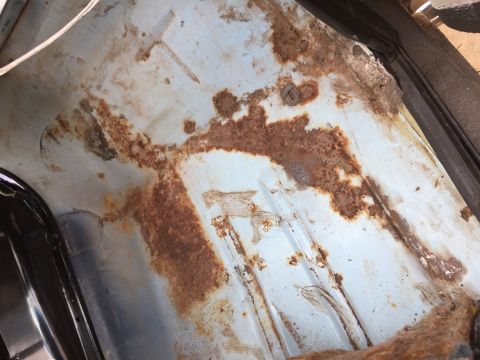 1978 Ford Bronco - The interior floor pan of a vehicle exhibits extensive rust and corrosion, indicating potential structural issues.