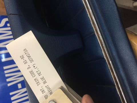 1978 Ford Bronco - A trim sample card for 'NIGHT BLUE MET.' is held against a blue interior surface, possibly for a vehicle from 1981-1982.