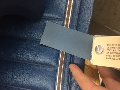 1978 Ford Bronco - A swatch of blue material is held against a blue vinyl seat, with text visible on the swatch holder.