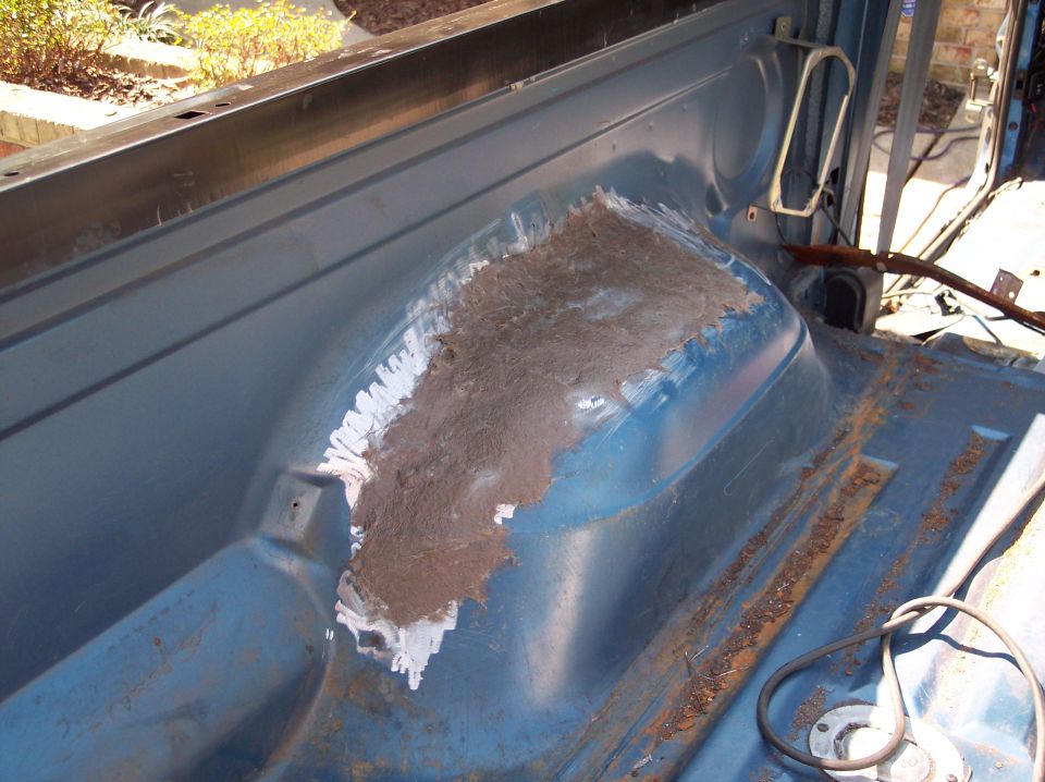 Interior of a vehicle with rust repair on the wheel well. Some body filler is visible