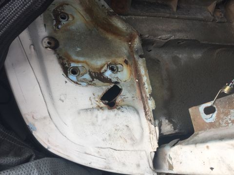 1978 Ford Bronco - Close-up view of rusted metal frame with bolt holes and a black opening.