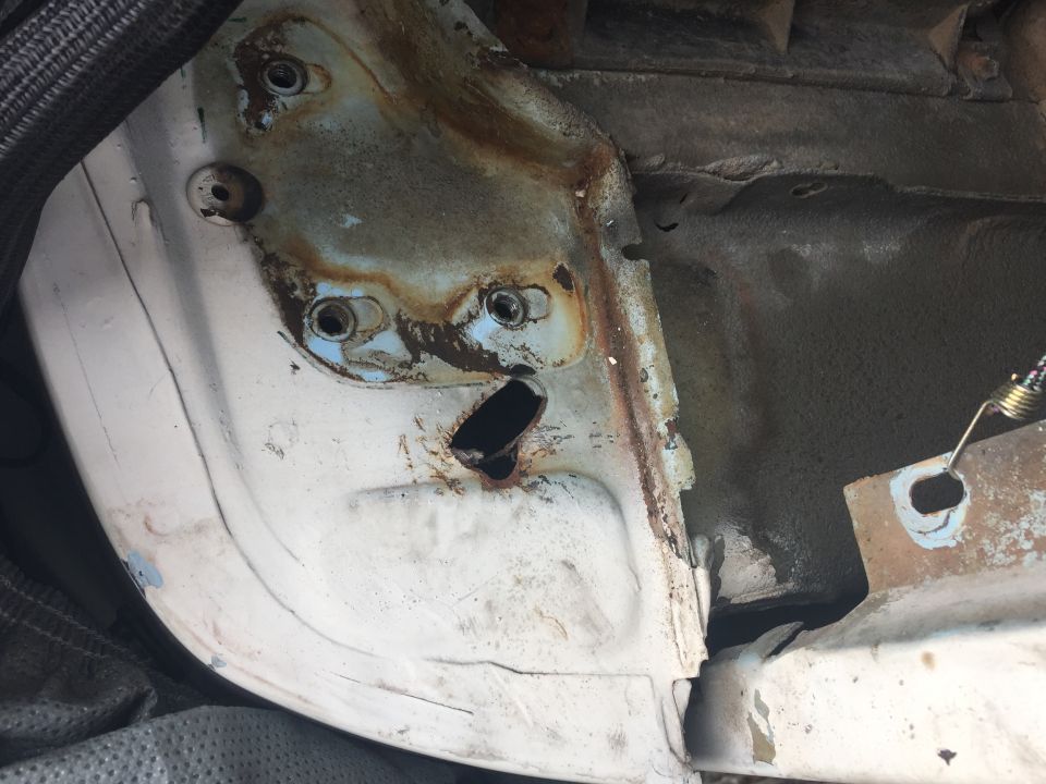 rusted metal frame with bolt holes and a black opening