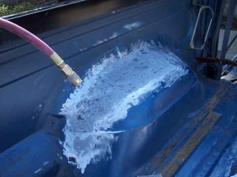 1990 Ford Bronco - Sandblasting a blue vehicle body panel to prepare for repair.