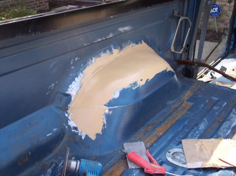 1990 Ford Bronco - Body repair work in progress on the interior of a vehicle, showing filler on the wheel well.