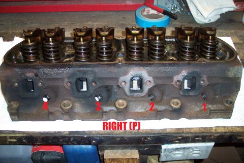 1995 Ford Bronco - A disassembled engine cylinder head sits on a workbench, ready for inspection or repair.