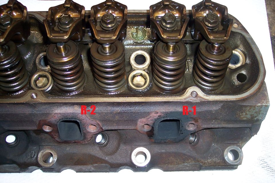 Engine cylinder head with visible rocker arms and valve springs, marked R-1 and R-2