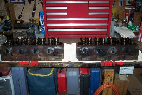 1995 Ford Bronco - Two engine cylinder heads sit on a workbench in front of a red toolbox.