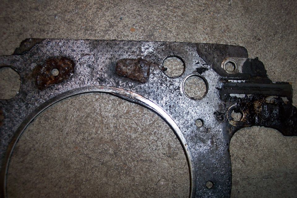 Close-up of a damaged engine gasket with rust and oil residue