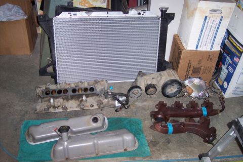 1995 Ford Bronco - Various engine components are laid out, including a radiator, intake manifold, valve covers, and exhaust manifolds.