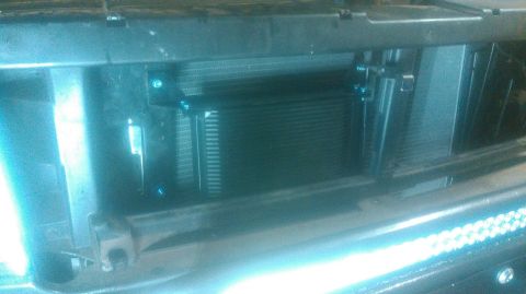 1992 Ford Bronco - An aftermarket finned transmission cooler mounted in front of the radiator and condenser behind a truck's front bumper and grille opening,…