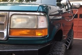 1996 Ford Bronco - Close-up of a green Ford Bronco's front corner, showing the headlight and grille area.