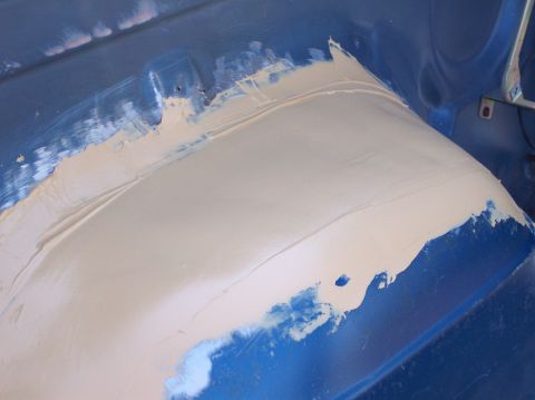 1990 Ford Bronco - Bodywork in progress on a vehicle's interior panel, with filler applied over blue paint.