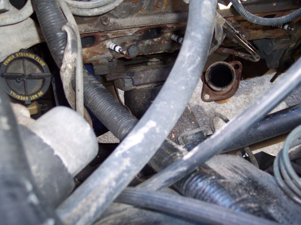 Engine bay with exhaust manifold removed exposing spark plugs and power steering cap