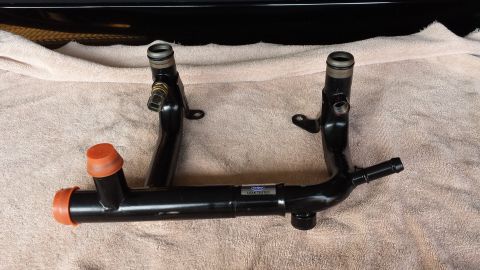 2005 Mercury Grand Marquis - A black metal water pipe assembly with orange caps is shown, likely a replacement part for a vehicle.