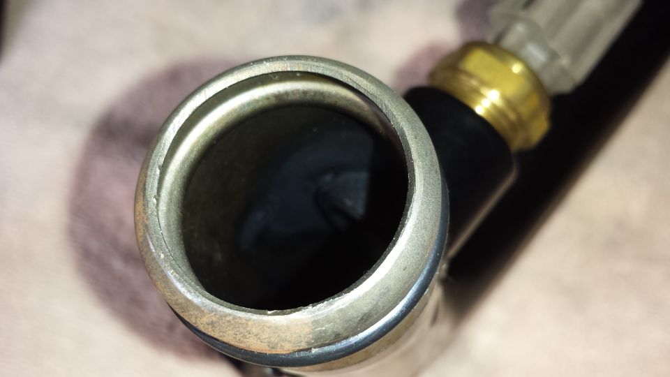 Close-up of metal pipe fitting or hose end opening with brass connector beside it