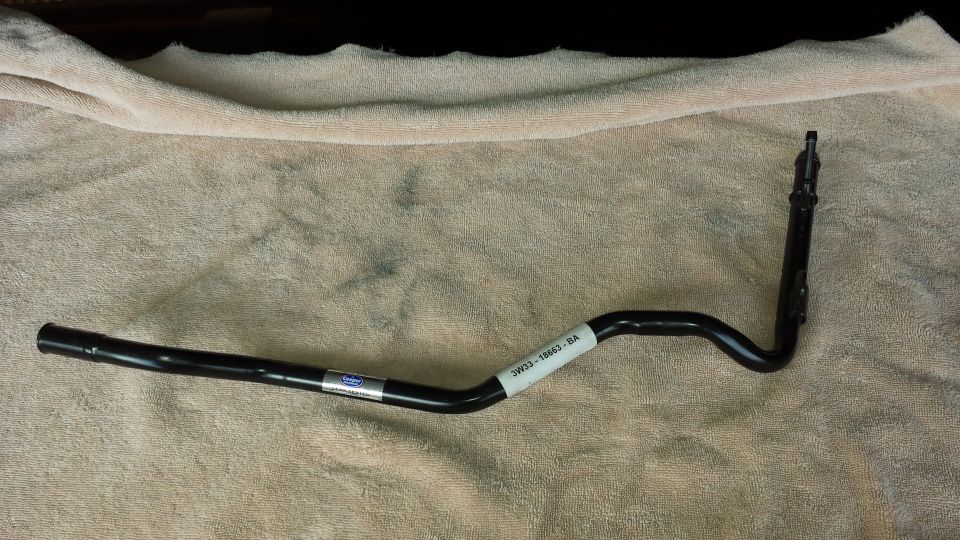 Black metal automotive part with labels, lying on a textured cloth