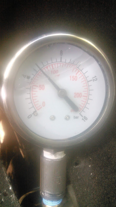 1992 Ford Bronco - Close-up of a chrome-bezel mechanical pressure gauge with a white face, dual red psi and black bar scales reading to 250 psi / 16 bar, plum…