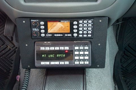 2001 Ford Crown Victoria - A dash-mounted radio console under a car's floor-carpeted center stack holds a Uniden BC780XLT TrunkTracker III scanner tuned to a sheriff/…