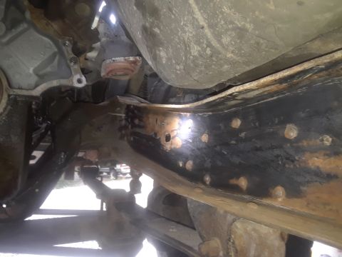 1996 Ford F-350 - The underside of a truck reveals significant rust on the frame and various mechanical parts.