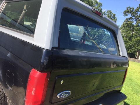 1996 Ford Bronco - This 1996 Ford Bronco features a two-tone black and grey paint scheme and a prominent Ford badge on the tailgate.