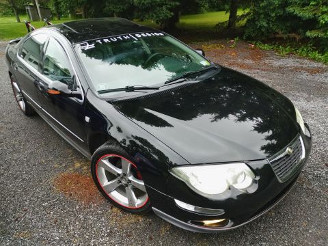 2002 Chrysler 300M - Front 3/4 view of a black 2002 Chrysler 300M with custom wheels and a windshield banner.