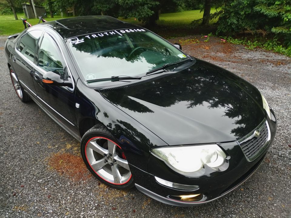 Black 2002 Chrysler 300M parked on gravel, front passenger side visible. Windshield banner reads "TRUTH DESIG…