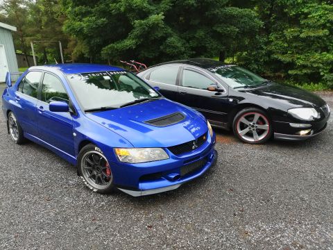 2002 Chrysler 300M - Two sedans, a blue Mitsubishi Lancer Evolution IX and a black Chrysler 300M, are parked side-by-side outdoors.