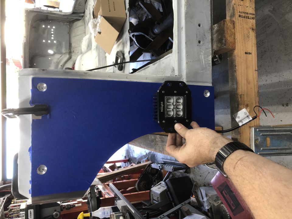 Black LED light with four bulbs attached to blue fender liner inside a vehicle