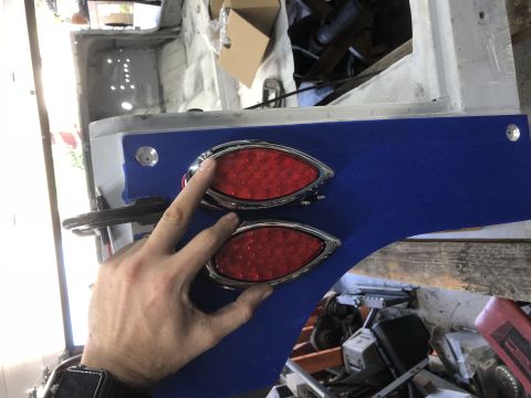 1992 Jeep Wrangler - A person is installing custom oval-shaped red LED taillights onto a vehicle's blue-painted panel.