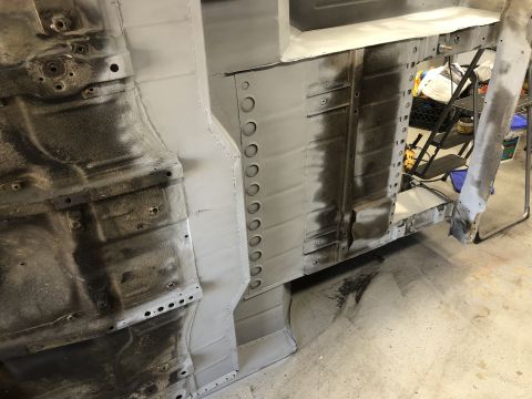 1992 Jeep Wrangler - Vehicle frame and body panels undergoing restoration work, showing metal preparation and primer application.