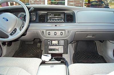 2001 Ford Crown Victoria - The interior of a police vehicle features a dashboard with radio equipment and a steering wheel.
