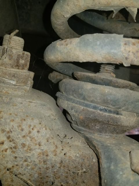 1996 Ford Bronco - This image shows heavily rusted suspension components, likely from the underside of a vehicle.