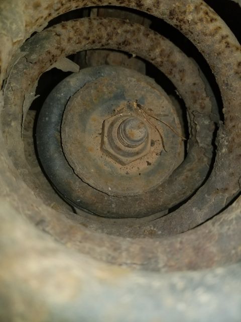 1996 Ford Bronco - This image shows a heavily rusted suspension coil spring and a bolt, likely from the undercarriage of a vehicle.