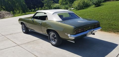 1969 Pontiac Firebird - A 1969 Pontiac Firebird convertible with a white top is parked on a concrete driveway.